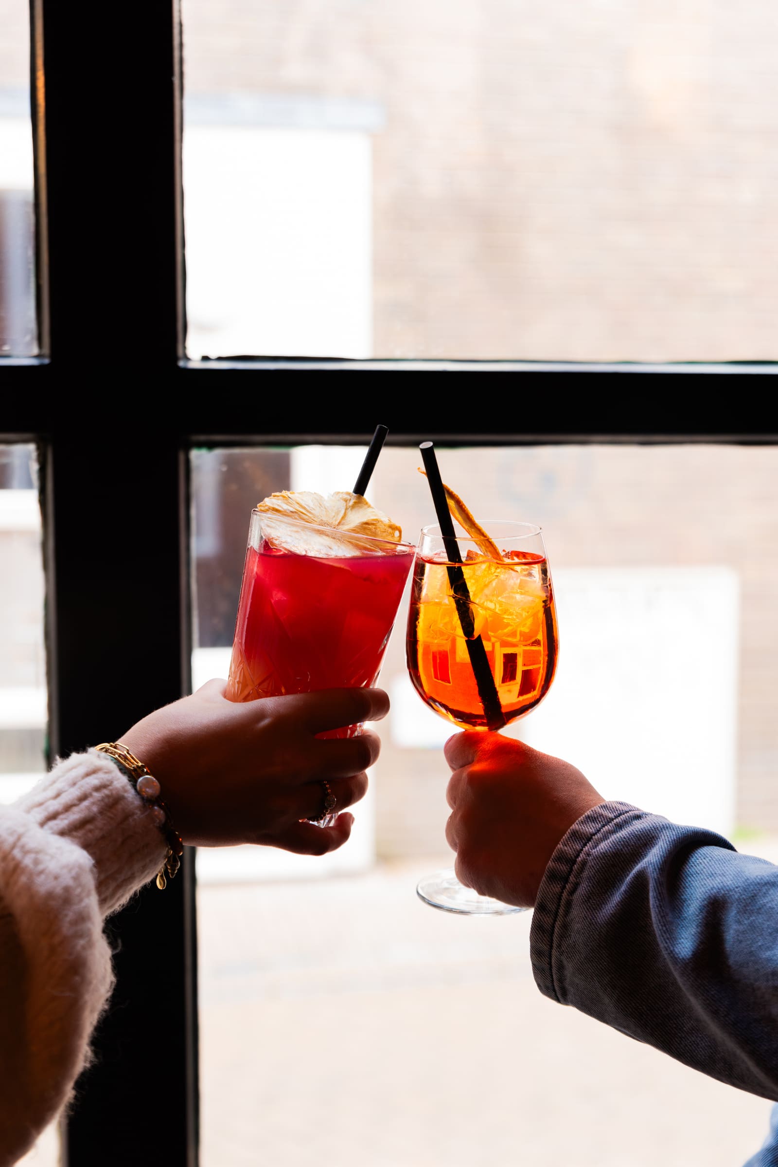 Twee cocktailglazen klinken tegen het avondraam